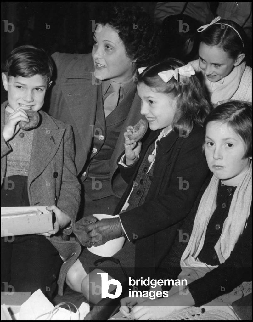 Second World War (1939-1945): a Corporal Wac (Women's Army Corps) of the US Army employee at the 9th US AF headquarters was able to find her little French cousins. Here they are around her during a tasting at HQ. Photography 3 January 1945.