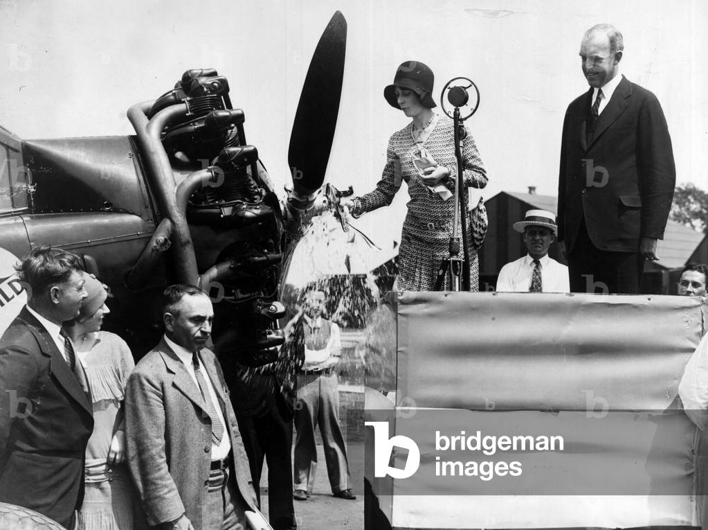Hoover Airport, Virginia, USA, August 15, 1929: Miss Dorothy Mills christens the first plane to fly Washington-Pittsburg. Next to her is the Assistant Secretary of State for Commerce W.P McCracken. At the foot of the stage, Mr. and Mrs. Clifford Ball (airline operator) and R.W Coates (air traffic manager) - Hoover field, Virginia, USA, 15th August 1929: Miss Dorothy Mills christening a plane of the new line connecting Washington to Pittsburg - Also present: Assistant Secretary of Commerce W P McCracken, operator of the line Clifford Ball and his wife, and traffic manager R W Coates