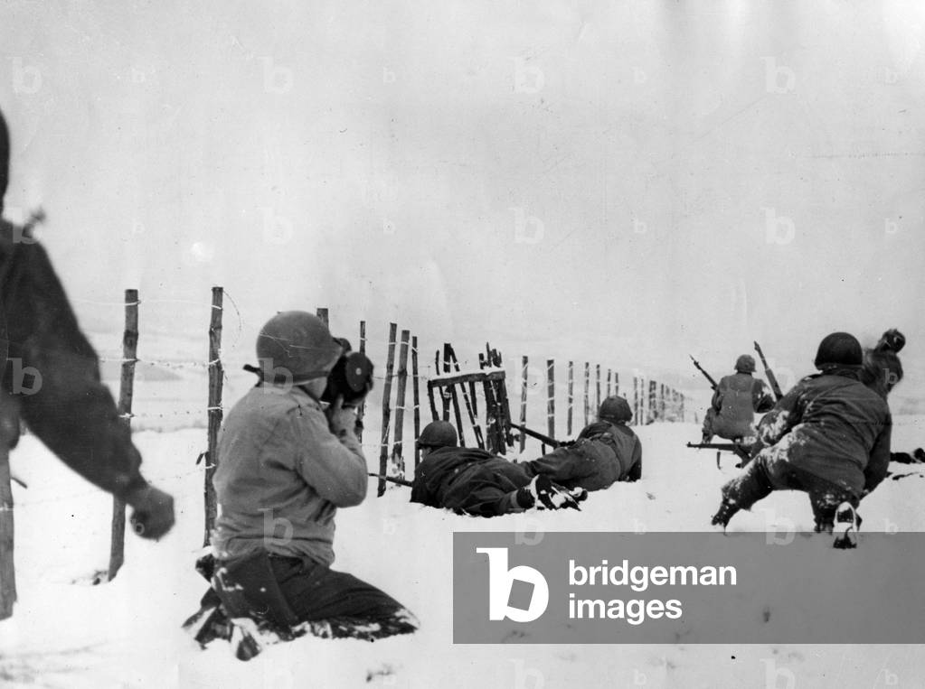 WWII - Battle of the Bulge (WWII - Battle of the Bulge): A soldier of the US Signal Corps films infantrymen of the 75th DI US looking for German snipers as they advance on the village of Beffe (Belgium), around January 6, 1945 - Photography