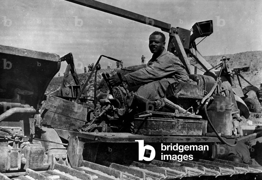 WWII:Normandy (France) Summer 1944: An African American soldier of a unit of Genie maneuvers a bulldozer