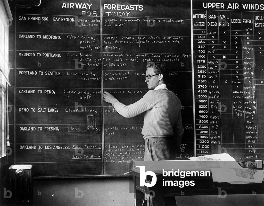 Oakland (California), USA, late 1920s: An employee of the City's Meteorological Service in front of the table that gathers all the meteos conditions of the city's aerodromes - Oakland, California, USA, end 1920s: comprehensive weather board in the main office of the aviation weather system, on which are posted notices of conditions over the various airways