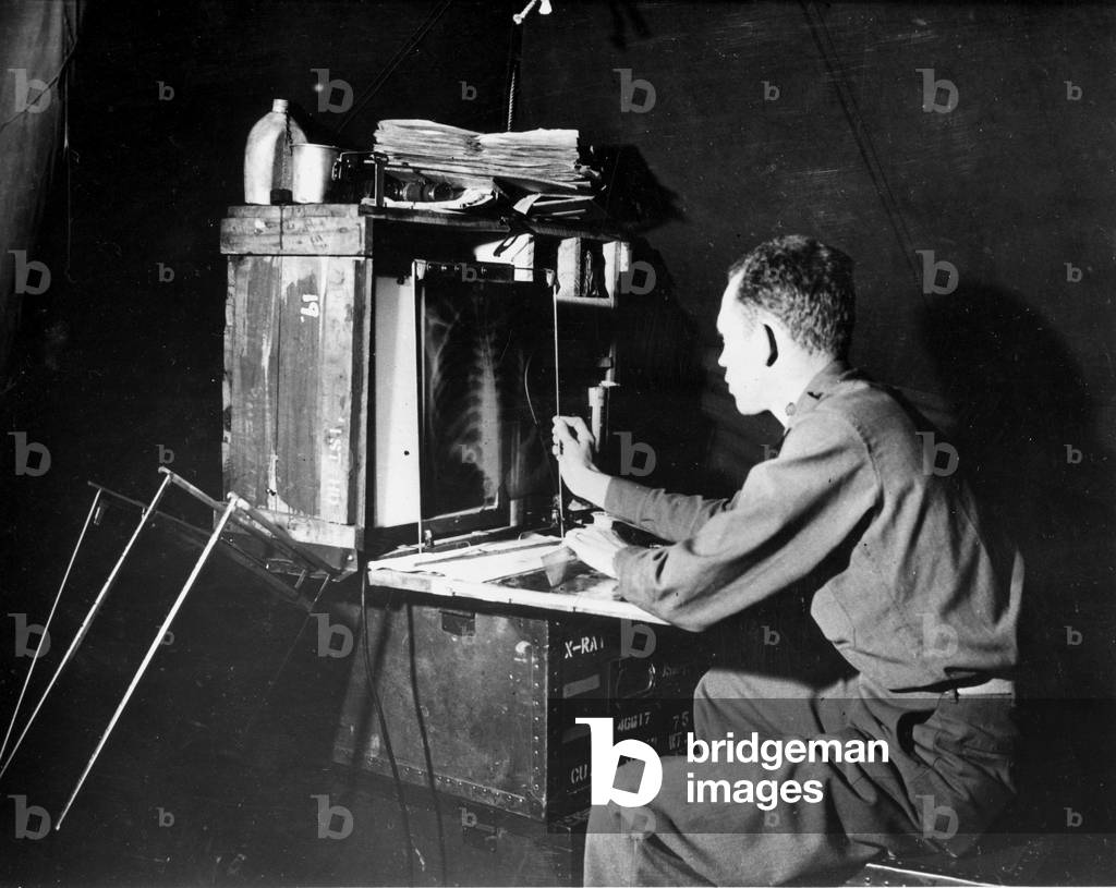 Second World War (1939-1945) (WWII): In a field hospital in Normandy, an American physician captain studies the radiology of a soldier wounds his chest - Photograph July 1944