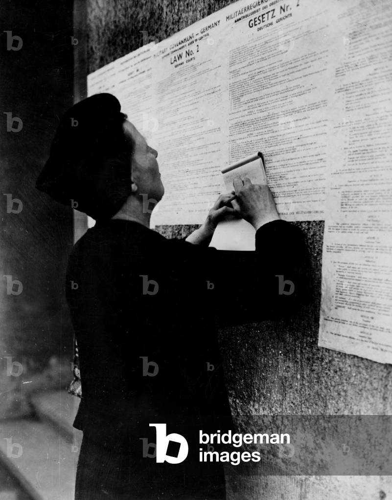 Second World War (1939-1945): Bamberg (Germany) April 14, 1945: After the capture of the city by elements of the 7th US Army, this woman takes notes before the opinion of the American Military Government placed on a wall.