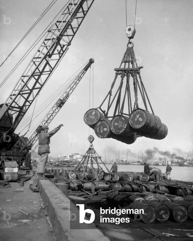 Fuel drums are lifted and moved with cranes from a tanker at Inchon Harbor, Korea. March 7, 1952. Korean War, 1950-53