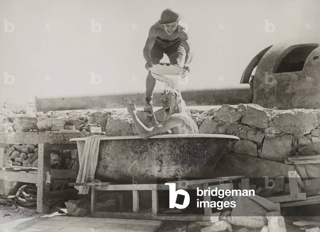 British soldier gives thumbs up for a bath near a coastal gun in the Western Desert. c. 1940-42 during World War 2