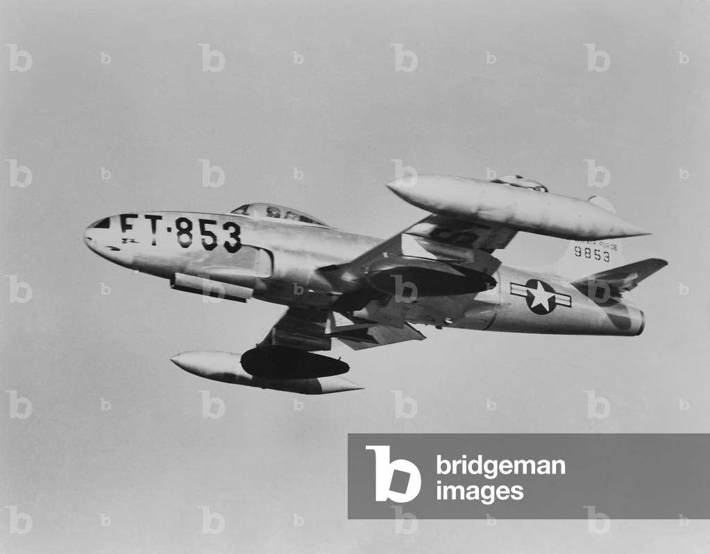 U.S. F-80 jet fighter carrying napalm in seventy five gallons dark colored wing tanks. Korean War, 1950-53