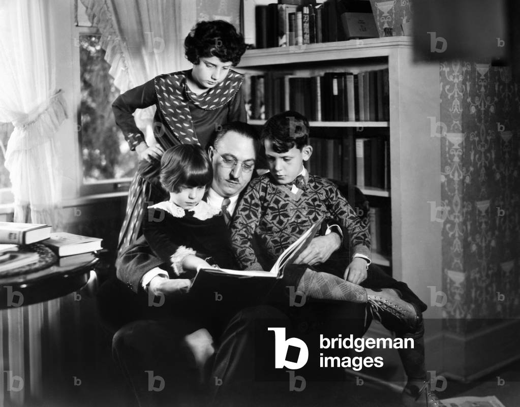 Dr. Karl A. Menninger, psychiatrist, with his children. c. 1930. They are playing anagrams. Julia is standing, while Martha and Robert sit with their father