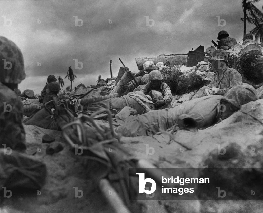 U.S. Marines take cover from Japanese fire behind a sea wall on Red Beach #3, Tarawa Island. Nov. 20, 1943