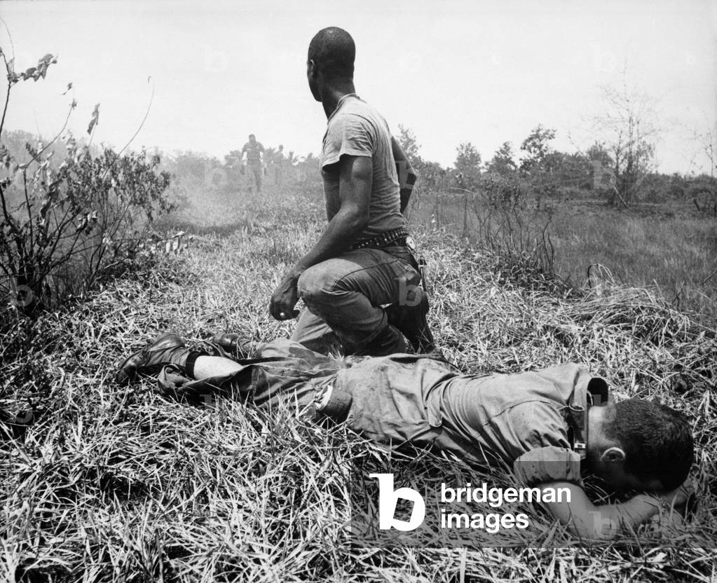 Vietnam War. An African American Infantry medic treats a lieutenant's leg, that was burned by an exploding Viet Cong white phosphorus booby trap. 1966