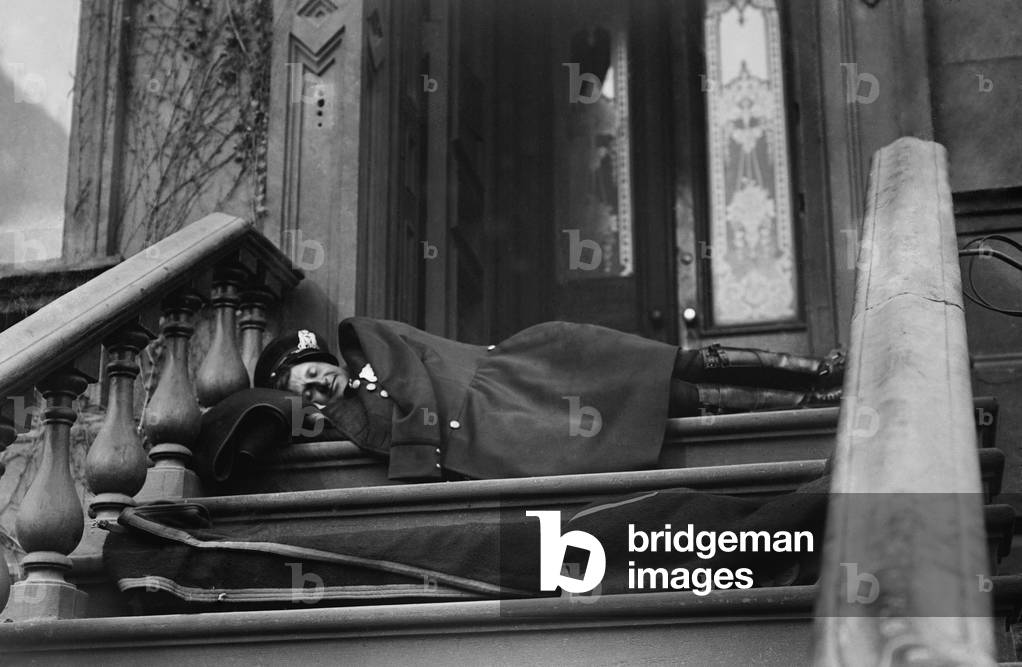 Policeman sleeping on the porch of a New York City brownstone during the strike by wagon drivers of Adams Express, American Express, and Wells Fargo. 1910