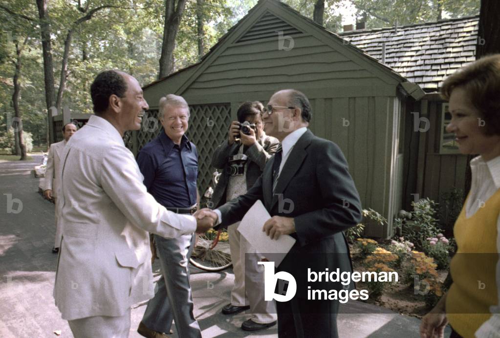 President Jimmy Carter watches Egyptian president Anwar Sadat (L) shake hands with Israeli prime minister Menachem Begin (R). First Lady Rosalynn Carter is at far right. Camp David, Maryland. 1978