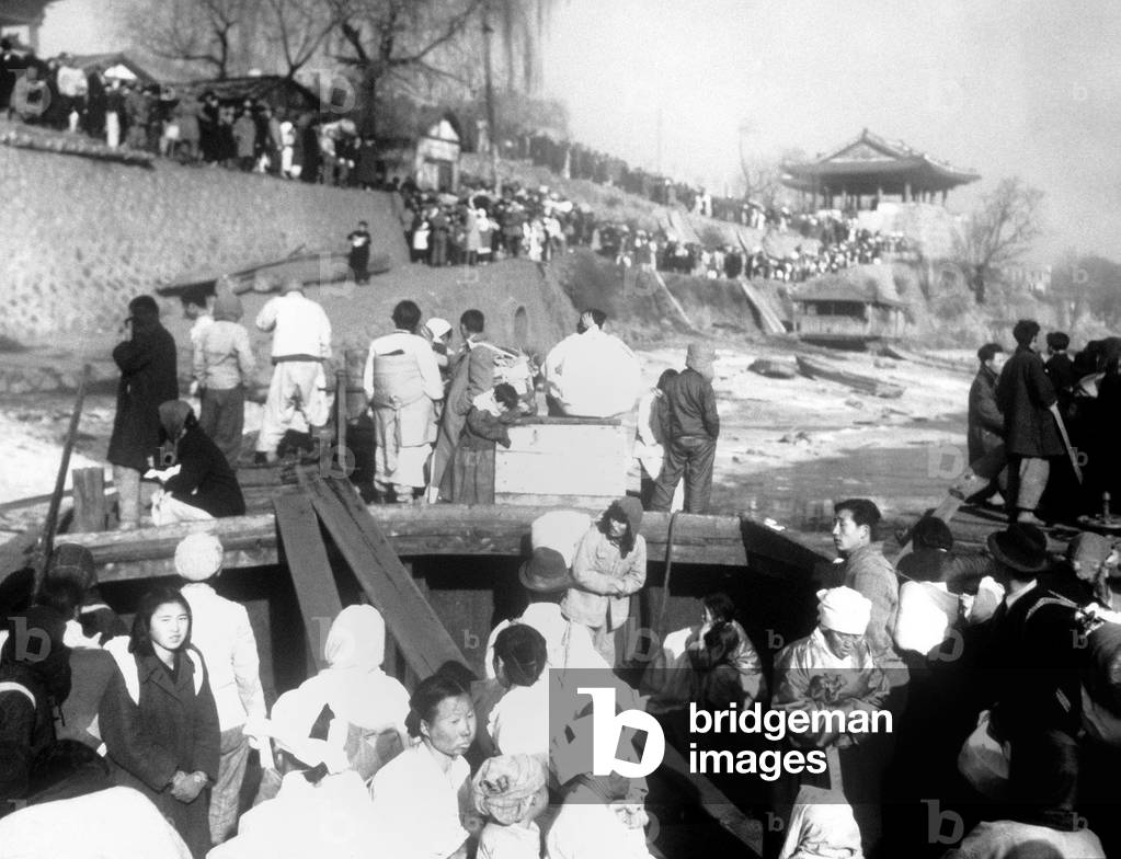 North Korean refugees are evacuated by ferry boats on the Taedong River at Pyongyang, Korea. They are fleeing the North Korean/Chinese troops approaching as the UN troops withdraw to South Korea. Korean War, 1950-53