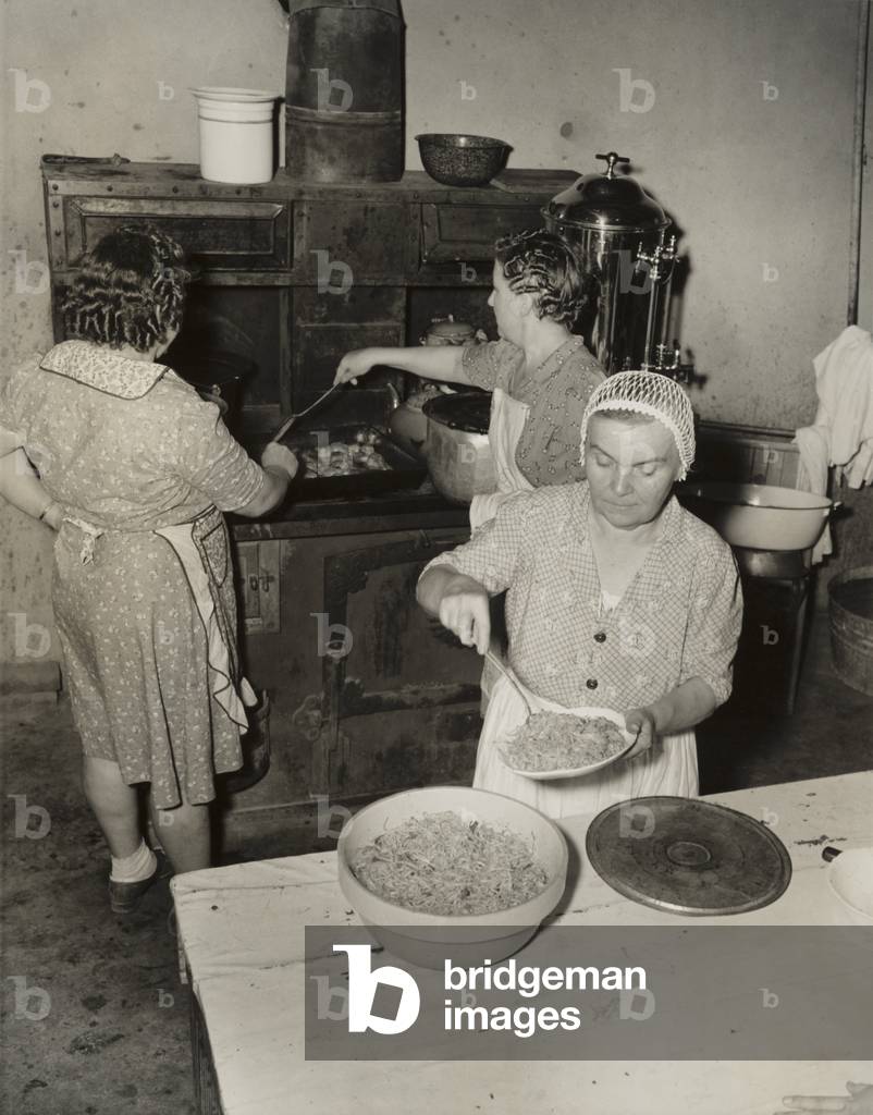 Women cooking spaghetti and frying chicken on an old stove for the Grape Festival. Tontitown, Arkansas. August 16, 1941.