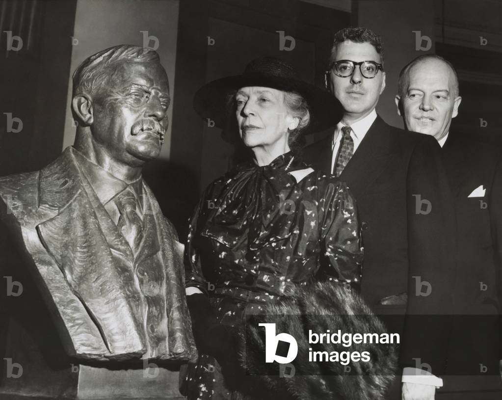 Remembrance as Theodore Roosevelt's bust is unveiled. Alice Roosevelt Longworth, Oscar Straus of the Theodore Roosevelt Association, and Harold Stassen, with the sculpture by Georg John Lober. In was installed in the Hall of Fame for Great Americans in the Gould Library at New York University. 1954.