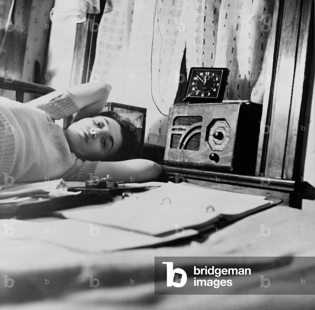 A young women listens to a radio in her Washington D.C. boardinghouse room. 1943