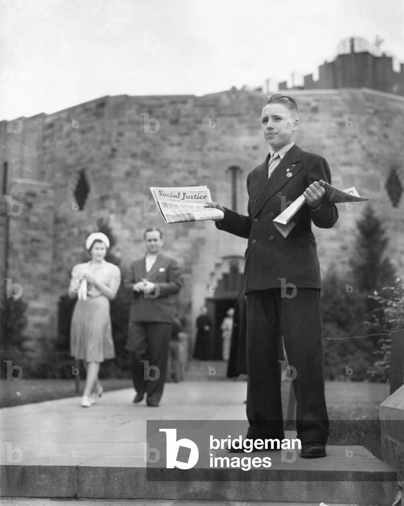 Teenager selling Father Coughlin's newspaper, 'Social Justice', July 1940. Behind him is the 'Shrine of the Little Flower' Catholic Church, Detroit, Michigan