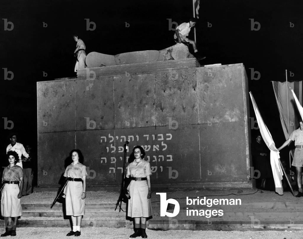Two youths light the eternal flame on top of Haifa's monument honoring those killed in the battle for Haifa one year earlier. The incription of the tomb reads: 'Honor and Praise to those who fell for the defence of Haifa'.