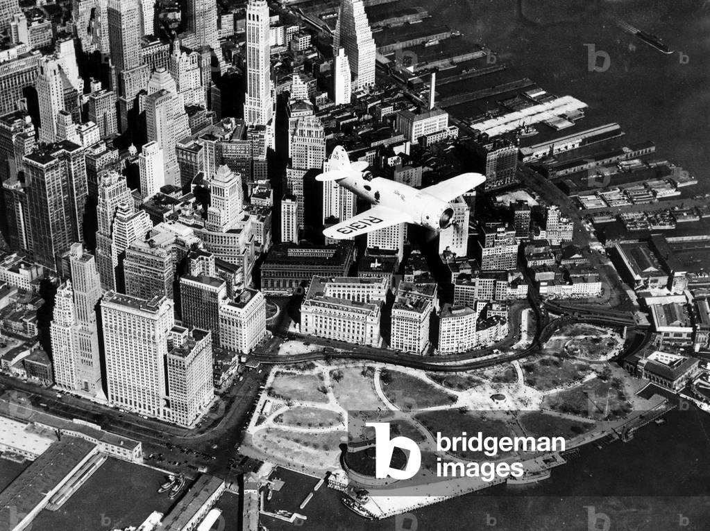Captain Frank Hawks' new Speed Plane flying over Manhattan's financial district and Battery Park, New York City, April 3, 1937