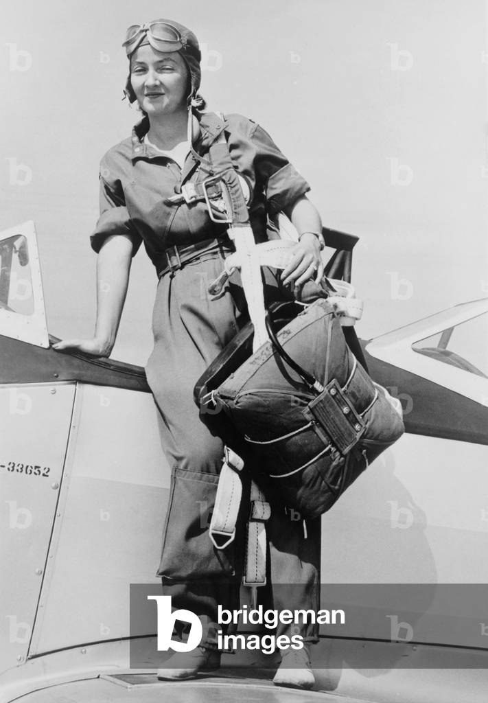 Nancy Harkness Love, wearing the uniform of the Women's Auxiliary Ferrying Squadron. She is standing on a airplane wing with her parachute harness slung over her shoulder. Sept. 16, 1942. World War 2