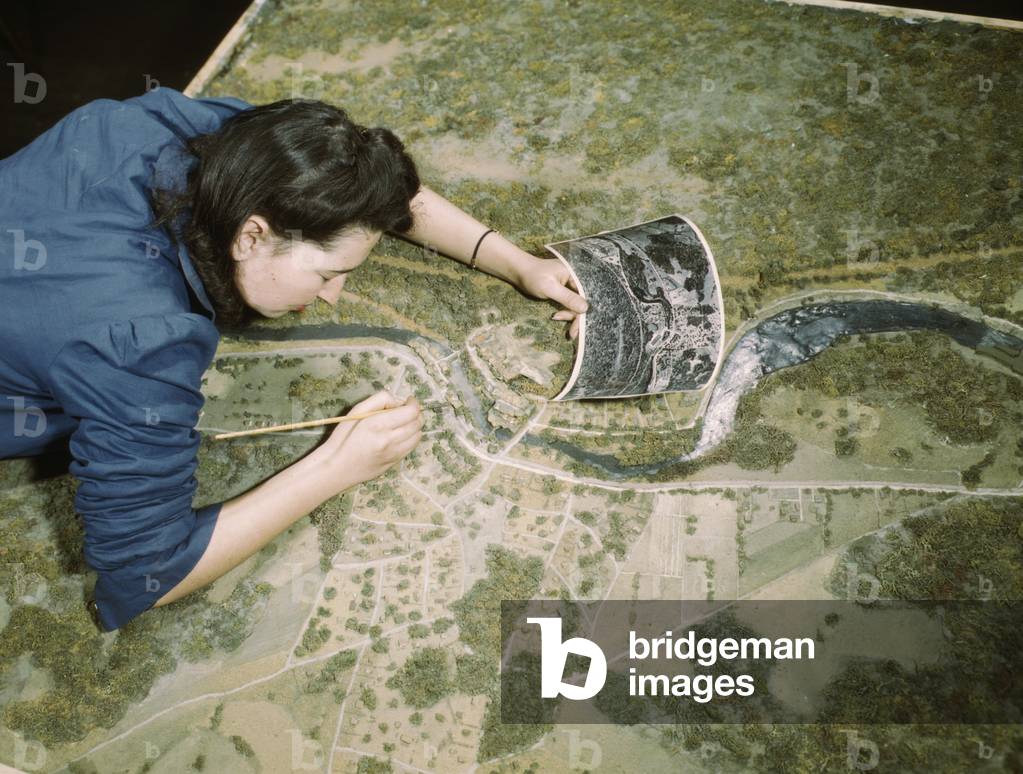 Young women in camouflage class at New York University during World War 2. She is disguising a model defense plant in preparation for jobs in the Army or in industry. March 1943