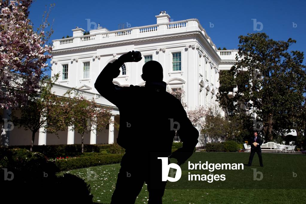 In the Rose Garden President Obama practices for the ceremonial first pitch for the opening game of the baseball season between the Washington Nationals and the Philadelphia Phillies. Assisting is White House trip director Marvin Nicholson. March 31 2010.,