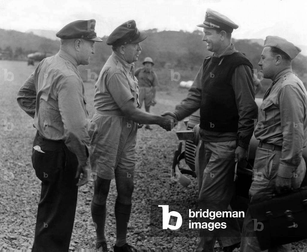 Congressman Lyndon Johnson visiting fighting commanders at an air base in New Guinea Island during World War II. Brig. Gen. Martin Scanlon shakes hands with Lt. Comdr. Lyndon Johnson. At far left is right is Brig. Gen. Ralph Royce and at right is Brig. Gen. William F. Marguat. July 1, 1942