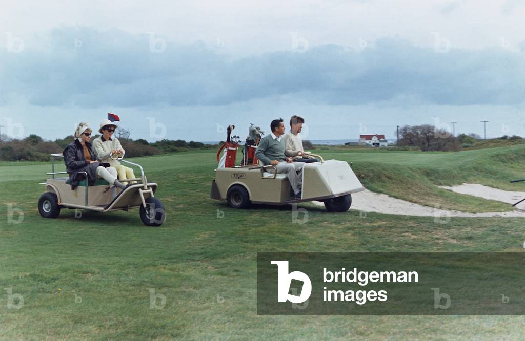 The Kennedys golf with the Ben Bradlees at the Newport Country Club. Antoinette Bradlee and Jacqueline Kennedy follow the golf cart of the President and Journalist Benn Bradlee. Sept. 14-15, 1963