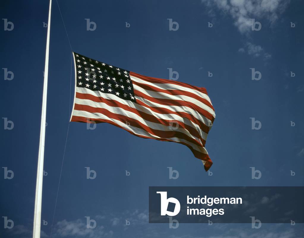 World War II, American flag, original caption: 'High above, over a true 'home of the brave,' the floating folds of the Star Spangled Banner symbolize the American way of life to soldiers in training for the battles that will bring freedom to an unhappy, wartorn world', photograph by Alfred T. Palmer, Fort Knox, Kentucky, June, 1942