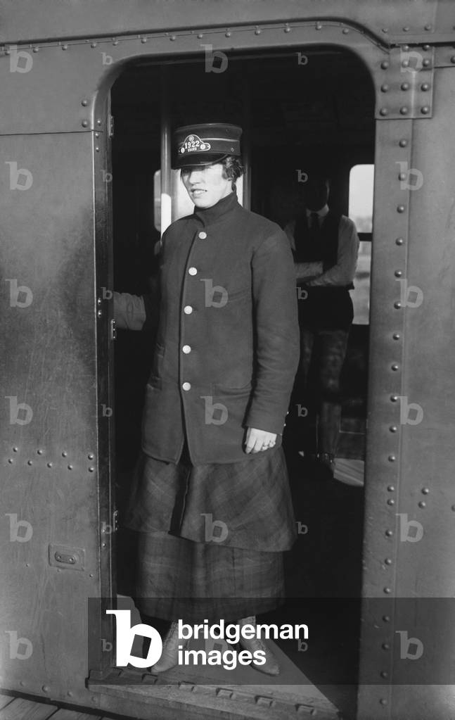 Uniformed woman Brooklyn Subway guard stands in the doorway of train car. c. 1910