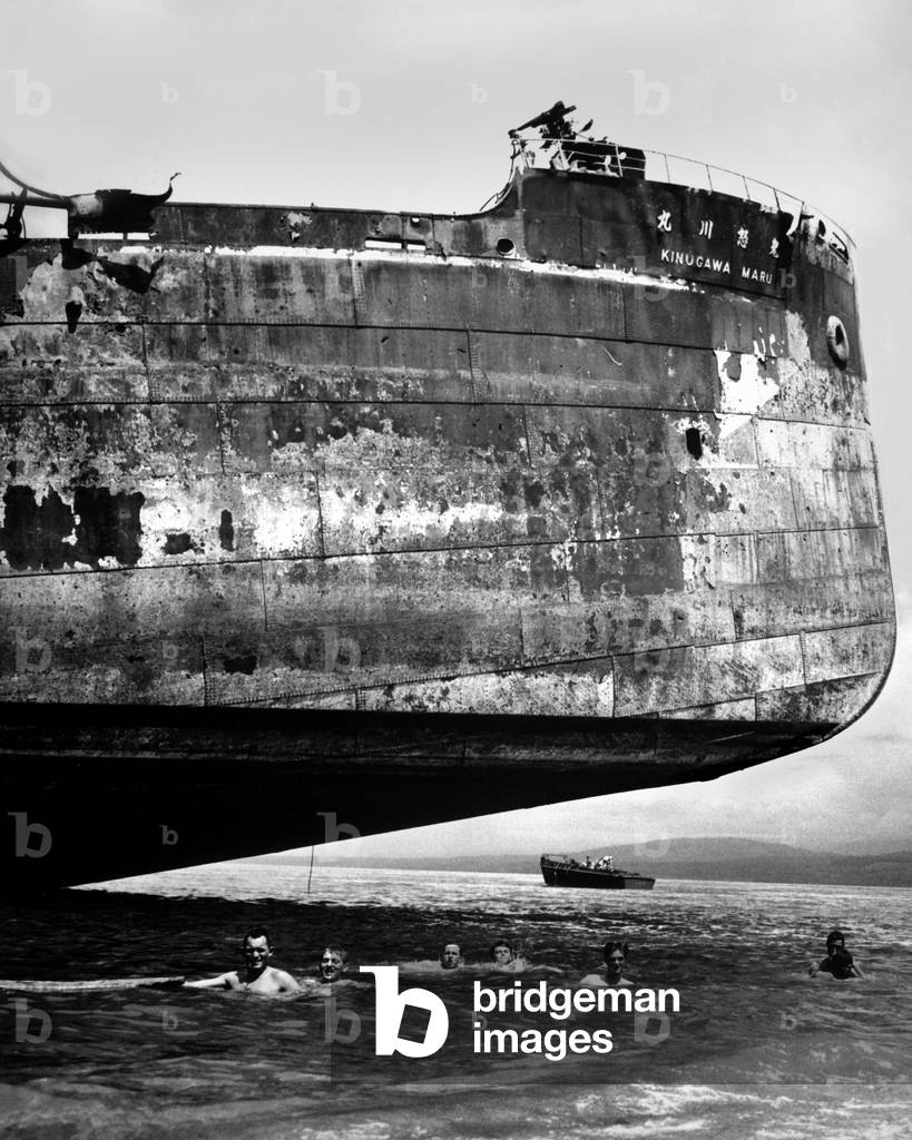 U.S. Coast Guardsmen swim near the wrecked Japanese transport, 'Kinuga Maru' at Guadalcanal. Kinugawa Maru sunk by Marine artillery and bombers from the USS Enterprise on Nov. 15, 1942