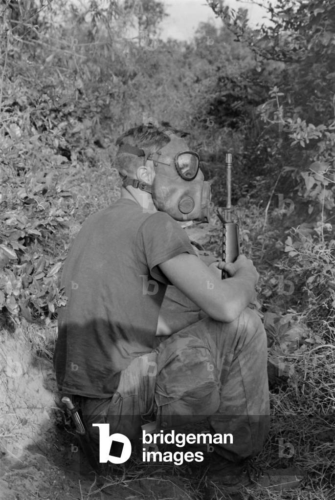 Vietnam War. US Marine wearing gas mask while waiting to enter a Viet Cong tunnel 22 miles south of DaNang, Vietnam. 1968
