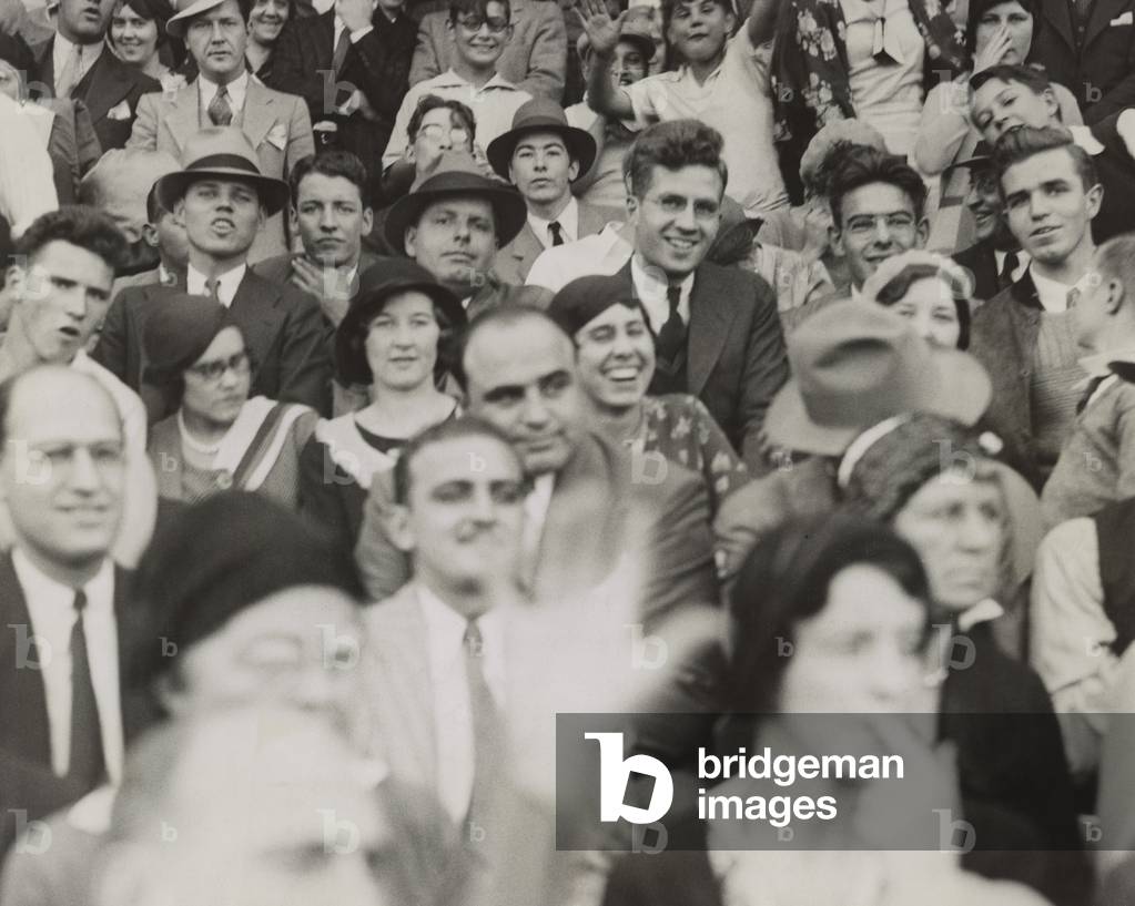 Al Capone (center), seated in front of three women, watching a college football game. He sits with other fans at the game between Northwestern and Nebraska at Dyche Stadium in Evanston, IL. Oct. 3, 1931.