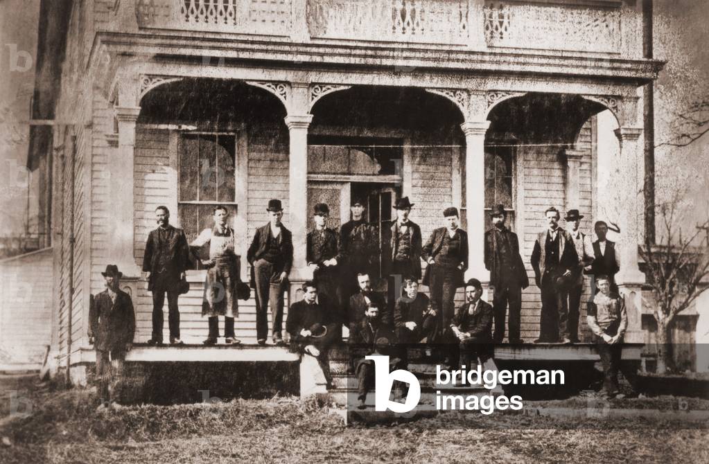 Thomas Edison with the engineers and technicians of his Menlo Mark workshop. Edison is under the central arch, leaning against the support with his hands in his pockets. c. 1880