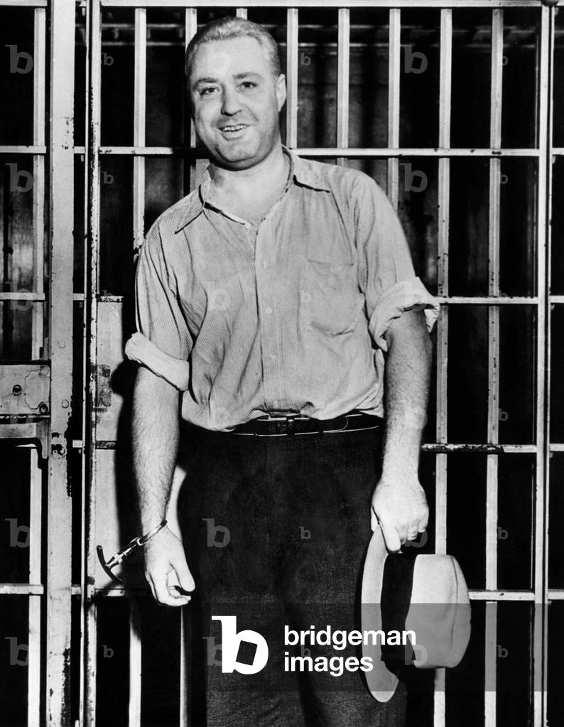 'Machine Gun' Kelly, handcuffed to cell bars, smiles for photographers in his Memphis jail cell. Sept. 26, 1933
