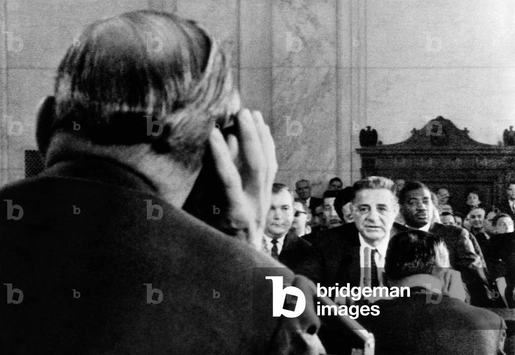 Joseph Valachi begins his testimony before the Senate Investigations Subcommittee. Valachi agreed to testify on the workings of the underworld crime empire, 'Cosa Nostra', as he said it was called. In the foreground is Sen. John McClellan who cups his oar to listen. Oct. 1, 1963