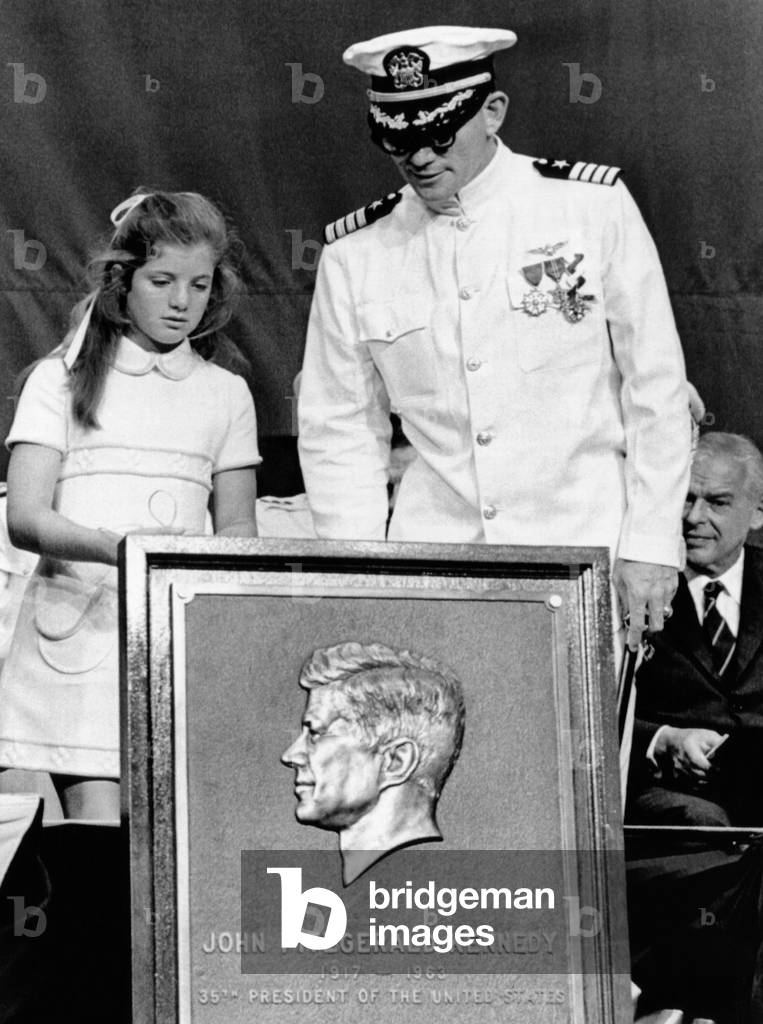 Caroline Kennedy with Capt. Earl Yates, commander of the newly commissioned aircraft carrier, USS John F. Kennedy. She presented him with a commemorative relief of her father, President John F. Kennedy. July 27, 1968