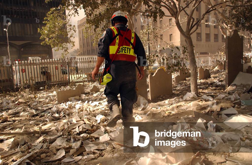 NYC firefighter walks among the old headstones at Trinity Church Cemetery in lower Manhattan. Sept. 19, 2001. The church grounds contain the graves of notable 18th and 19th century New Yorkers, including Alexander Hamilton and John Jacob Astor. New York City, after September 11, 2001 terrorist attacks