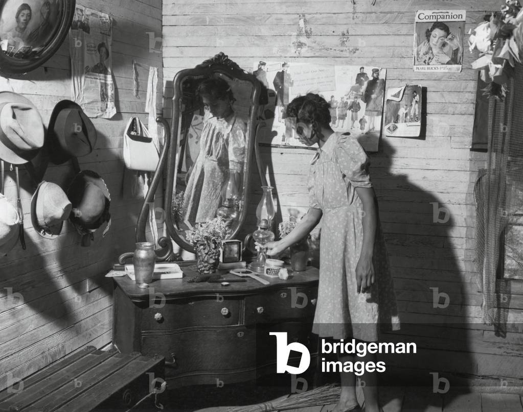 African American women at her dressing table in Putman, Georgia, 1941. The walls are decorated with family portraits and magazine advertisements