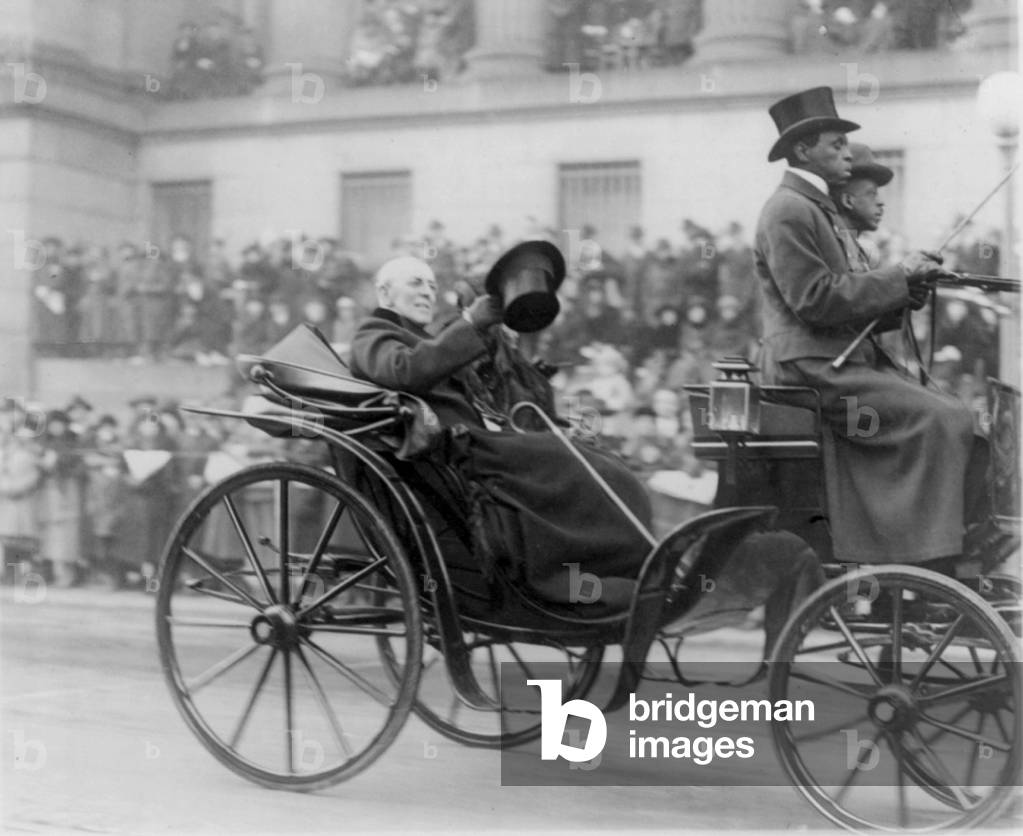 Woodrow Wilson (1856-1924) waving top hat to crowd from open carriage during Armistice Day 1919 procession for Unknown Soldier burial