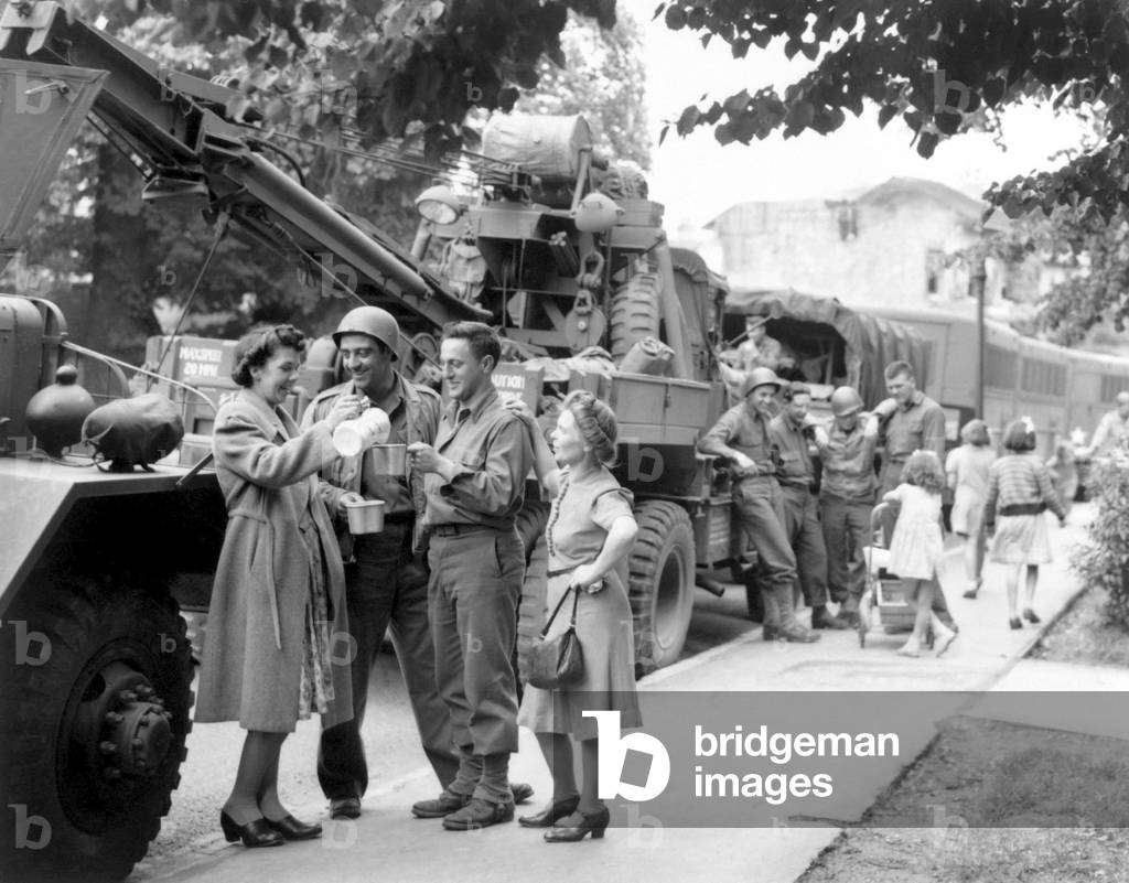 English townsfolk serve hot coffee to U.S. Army Ordnance men. They are awaiting their 'go' signal to join the ongoing invasion of France. July 24, 1944. World War 2