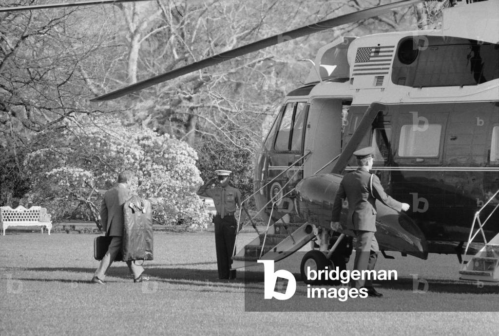 President Jimmy Carter walking toward Marine 1 the Presidential helicopter carrying his own luggage. c. 1977-80