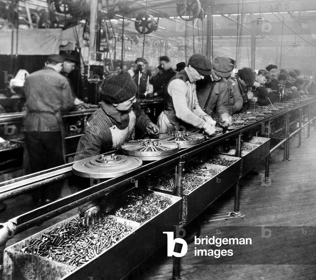 Men work on the flywheel magneto, the first manufactured part to be built on a moving assembly line, Ford Motor Company plant in Highland Park, Michigan, 1913