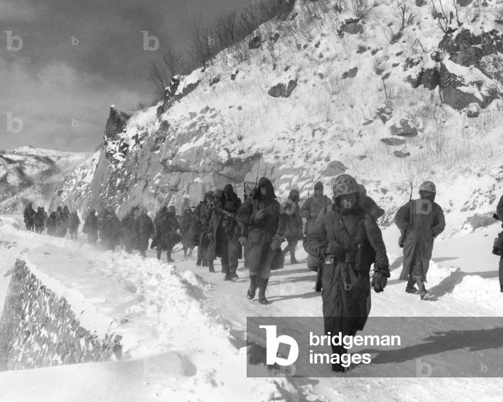 U.S. Marines march south from Kotori, withdrawing from the Chosin Reservoir in North Korea. Marines cleared the hills above the road of Chinese soldiers, allowing relatively safe passage in the sub-zero weather of mountains. c. Dec 10, 1950. Korean War, 1950-53