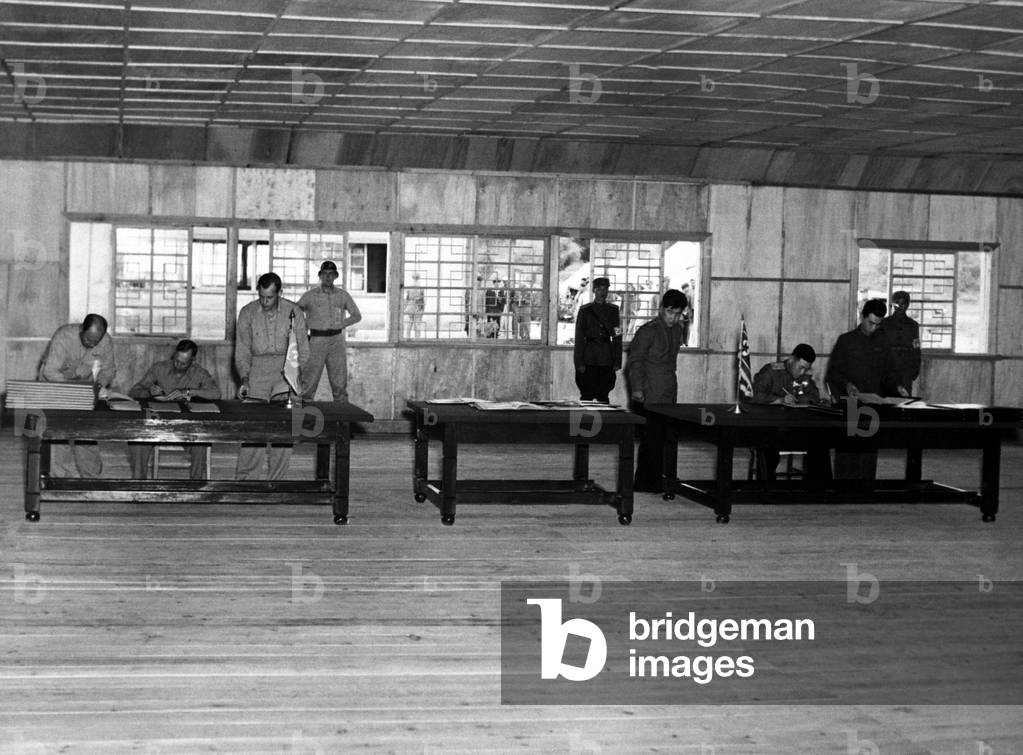Gen. William Harrison,(left table) signs armistice ending the 3-year Korean conflict. At the right table, North Korean Gen. Nam II, signs documents. Panmunjom, July 23, 1953. Korean War, 1950-53