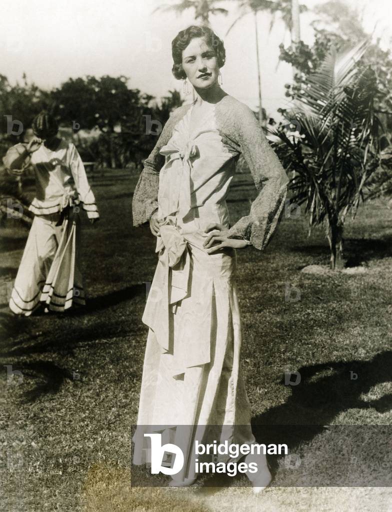 The annual mid-winter Miami Beach fashion show displays a long dress with a touch of lace about the shoulders, giving it an air of old Spain. c. 1925-30