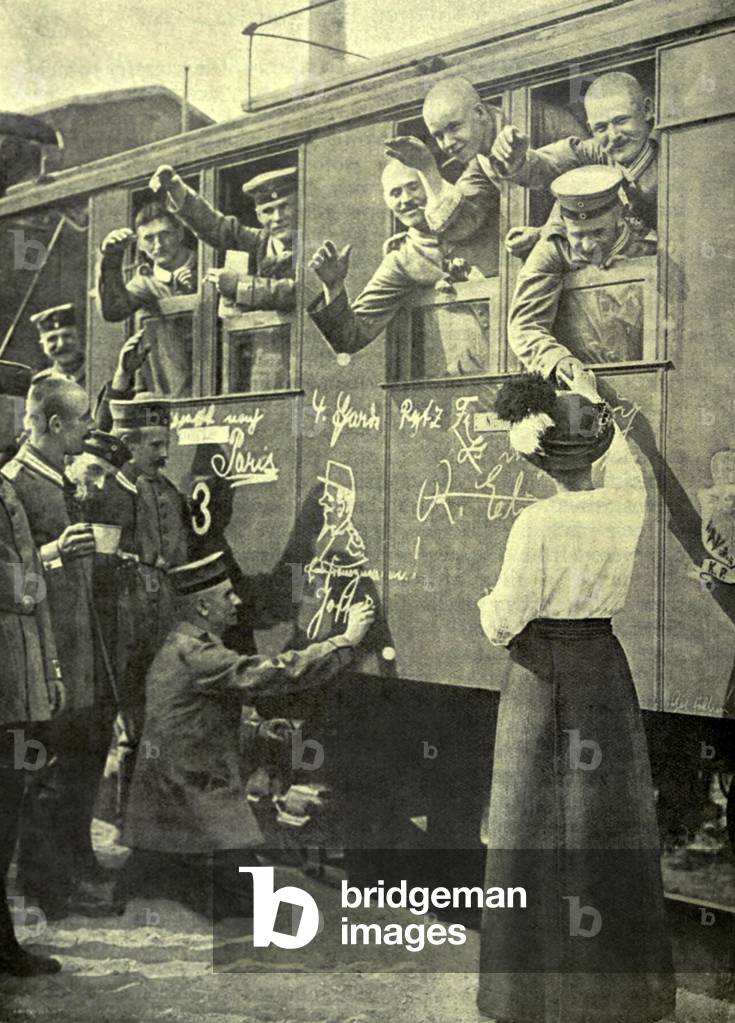 World War 1. German soldiers on a train bound for the Western Front in the first days of the war. A spectator draws a caricature of French General Joffre on the side of the railway carriage. August 1914