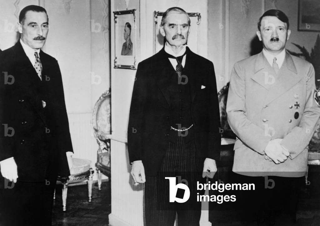 Neville Chamberlain, British Prime Minister in Munich. He stands between Sir Neville Henderson (left) and Adolf Hitler, in Hitler's hotel room, Godesberg, Germany in the summer of 1938. They were unable to resolve the Sudetenland crisis in this summer meeting and met again with a larger group at the Munich Conference in September
