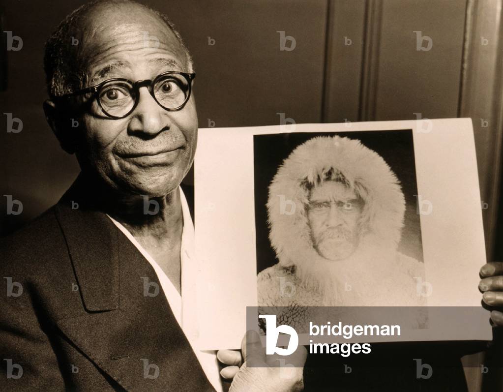 Matthew Henson (1866-1955), African American Arctic explorer, holding a portrait Admiral Robert E. Peary, his expedition leader. 1953