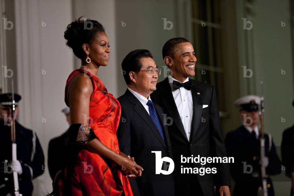 President and Michelle Obama welcome President Hu Jintao of China to the White House for the State Dinner Jan. 19 2011. Michelle wears a Chinese red evening dress of red petal print silk organza by Sarah Burton of Alexander McQueen with Ruby and geode earrings by Kimberly McDonald,