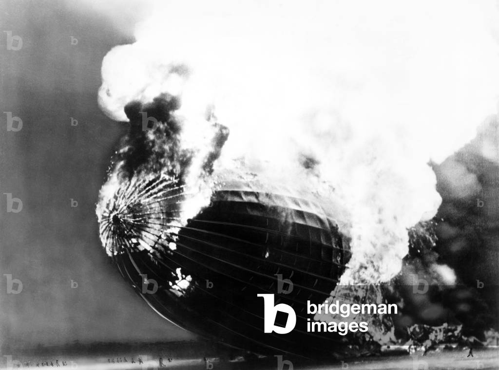 The Hindenburg disaster. People run away from the burning dirigible, dwarfed by its huge scale. May 6, 1937.
